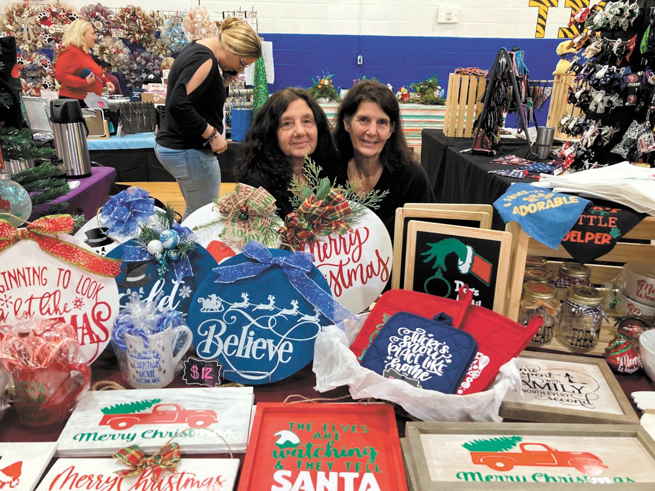 HOLIDAY SIGNS: If you’re in need of a holiday sign, custom bags or baby bibs, Becky Doughty (left) and Robin Pallini of Cutesy Crafts have you covered. Doughty started creating handmade signs several years ago, and she started selling them last year.